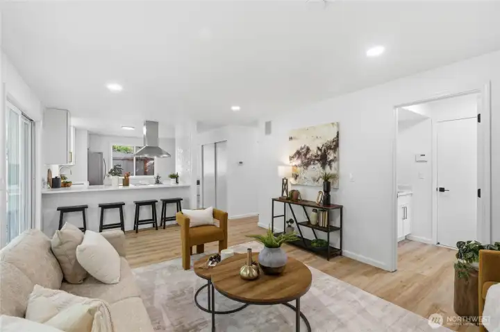 The open family room connects seamlessly to the kitchen peninsula and backyard slider, with recessed lighting, light wood floors, and a clean, airy feel throughout.