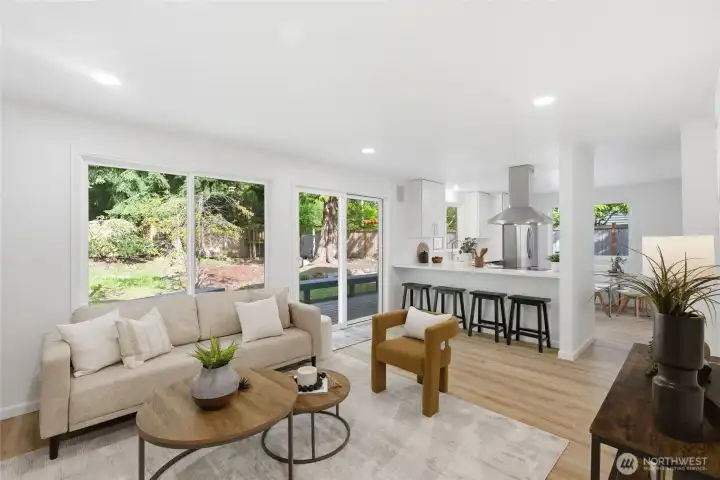 A wide-angle view captures the full open-concept layout — family room, kitchen peninsula, and backyard slider all connected with natural light pouring in from multiple directions.