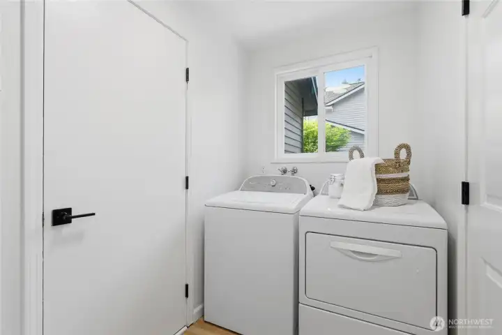 Dedicated laundry room with full-size washer and dryer, a window for natural light, and clean white finishes — conveniently located on the main floor.
