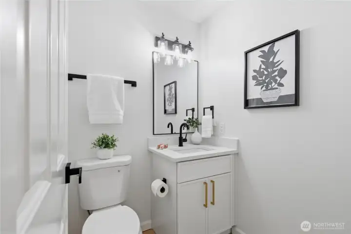 Stylish half bath with a white vanity, quartz countertop, matte black fixtures, and a statement vanity light — crisp and move-in ready.