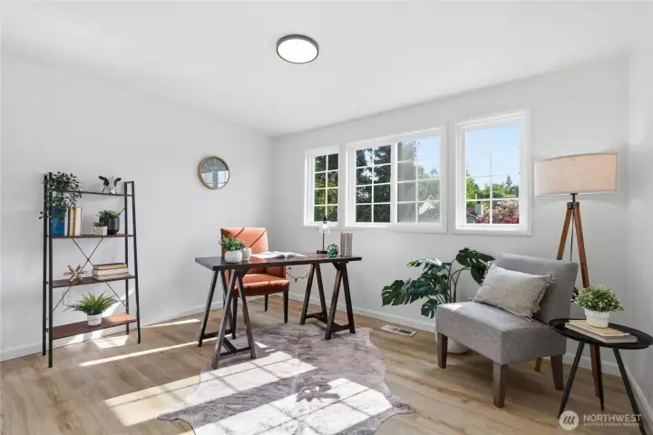 Sunlit flex room with large windows, light hardwood-style floors, and enough space to function as a home office, guest room, or additional bedroom.
