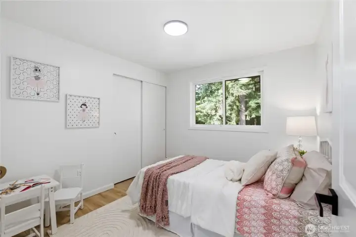 Well-sized bedroom with a sliding closet, bright window with greenery views, and light wood floors — versatile and freshly updated.