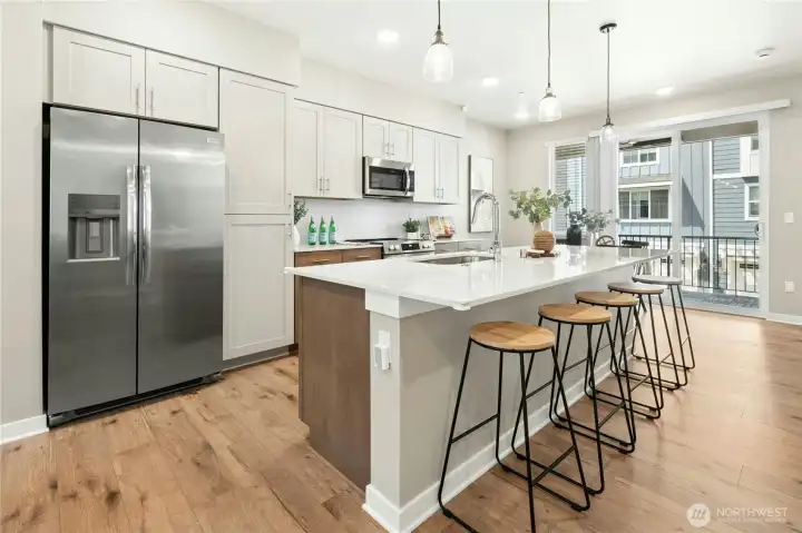 tunning kitchen with quartz countertops, full-height tile backsplash, and oversized entertaining island.