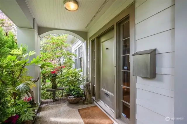 Covered entry porch lushly screened from the street - with metallic painted front door