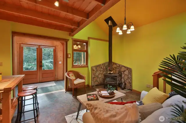 View from the main living space looking back at French door entry. The wood stove creates a toasty warm environment. Loft is above you, bathroom is behind you, stairs to the loft are on the right edge of this photo.