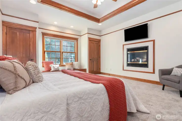 The main-floor primary suite is a serene retreat, featuring a cozy window seat, a warm fireplace, and a spacious walk-in closet.