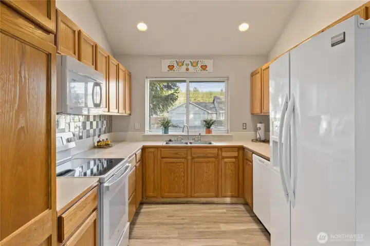 Double Stainless Sink, and lots of Counter Space! The Designer Tiles and White Appliances add reflective light to the kitchen.