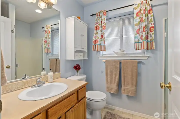 Main Bathroom in hallway. Cute Storage Cabinet and Large Window that opens for fresh air. Shower is to the right of the picture and behind the door is the full size Washer and Dryer that stay with the home.