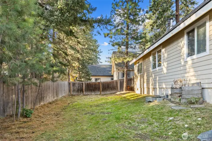 Partially Fenced Back Yard. Window on the right is the Primary Bedroom.  Two at other end are to the Main Living Area.