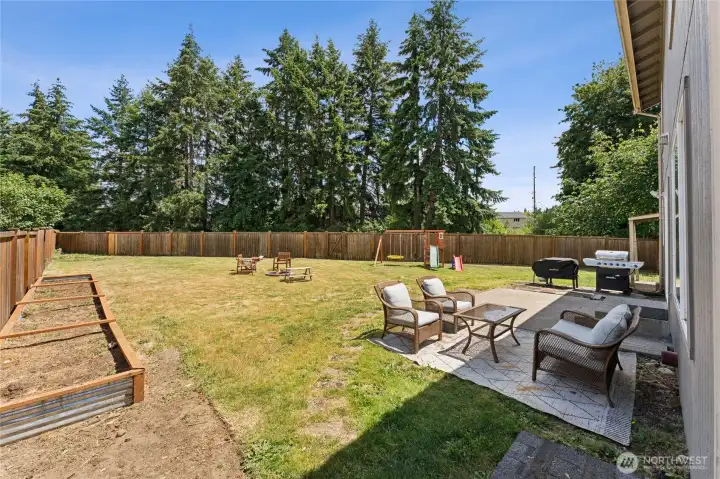 spacious fully fenced backyard featuring mature trees, raised garden beds, a storage shed, and playset that will remain with the home. spacious fully fenced backyard featuring mature trees, raised garden beds, a storage shed, and playset that will remain with the home.