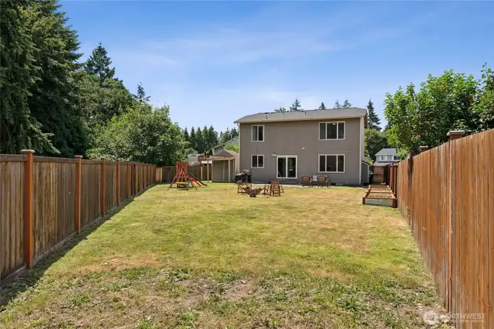 spacious fully fenced backyard featuring mature trees, raised garden beds, a storage shed, and playset that will remain with the home. spacious fully fenced backyard featuring mature trees, raised garden beds, a storage shed, and playset that will remain with the home.
