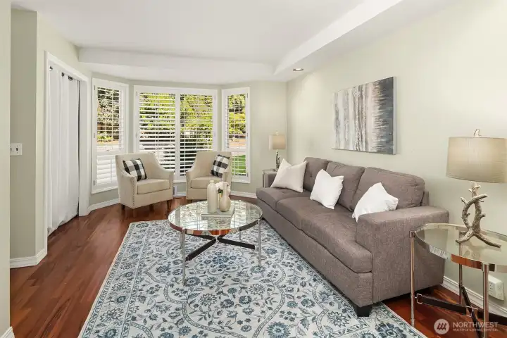 Light-filled living room features hardwood floors, large windows, and views of the front yard Light-filled living room features hardwood floors, large windows, and views of the front yard