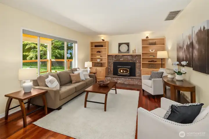 Inviting living room with woodburing fireplace, hardwood flooring, and views of the surrounding landscape Inviting living room with woodburing fireplace, hardwood flooring, and views of the surrounding landscape