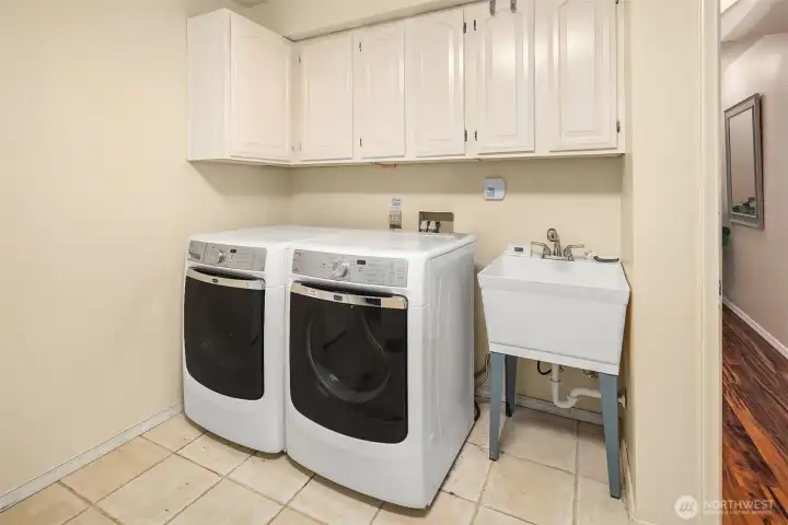 Dedicated laundry room with storage cabinets and utility sink for added convenience. Dedicated laundry room with storage cabinets and utility sink for added convenience.