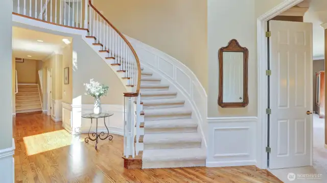 Grand curving staircase leads to more luxury (primary suite entrance on right)