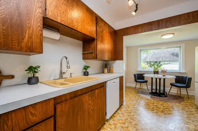 The cheerful kitchen features ample cabinet and counter space, a cozy breakfast nook with access to the backyard and Trex deck, classic beadboard ceiling detail and eye-catching geometric vinyl floors-- blending character with everyday functionality!