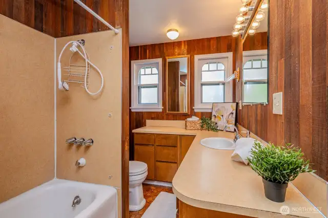 Step into the hallway from the Kitchen and you'll find the main floor Full Bath with large mirrors, ample storage & counter space, a bath/shower combo and commode. Retro with a nostalgic touch...