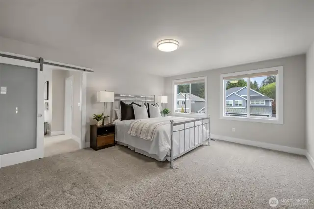 Grand primary suite with double door entry and barn door to bath. Large window in the primary suite fills the room with natural light.