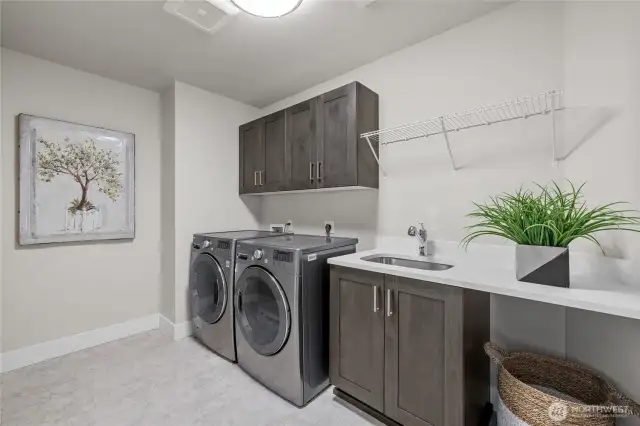 Laundry room upstairs with sink, cabinets, and room for added shelves.