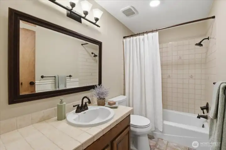 Main bathroom with tile countertops, flooring, and shower tub combo. Main bathroom with tile countertops, flooring, and shower tub combo.