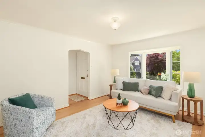 The sunny, spacious living room with bay windows and beautiful entry