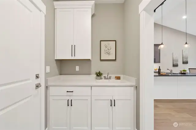 Upper & lower cabinets and laundry sink on one side of the utility room.