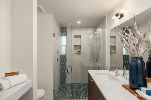 The frameless glass shower with striking tile accents and built-in shelving exudes modern elegance. This inviting space transforms everyday routines into a spa-like experience.