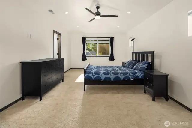 Primary bedroom with large windows overlooking the backyard.
