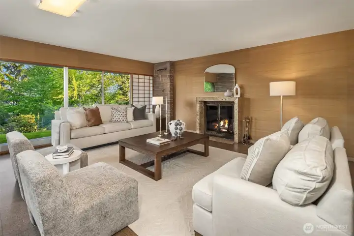 The expansive living room has a wood buring fireplace, grasscloth wallpaper and terrazzo floors