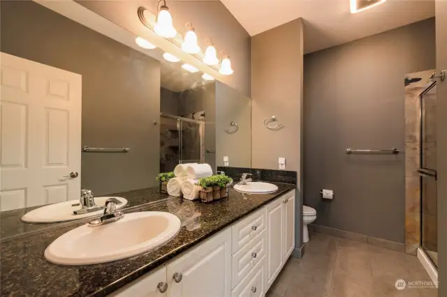 Double vanity and oversized walk in closet  provide room to move around with added storage above the commode.
