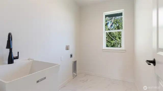 Laundry room with tile flooring and utility sink.