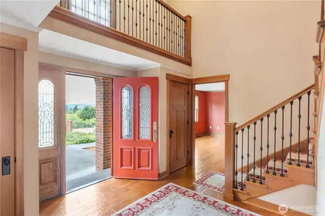 Entry with wrap around walkway/built in on second floor, stairs leading up and pocket glass doors to the left into the family room and to the right into formal dining room with built in cabinetry.