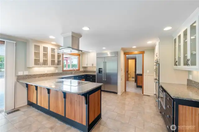 Looking at kitchen showing off sit down bar and newer large refrigerator. Also show off plenty of room for help preparing meals for family & gatherings.