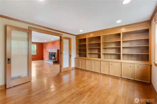 Office with built in cabinets and shelving on the right and dual glass doors looking into Family room.