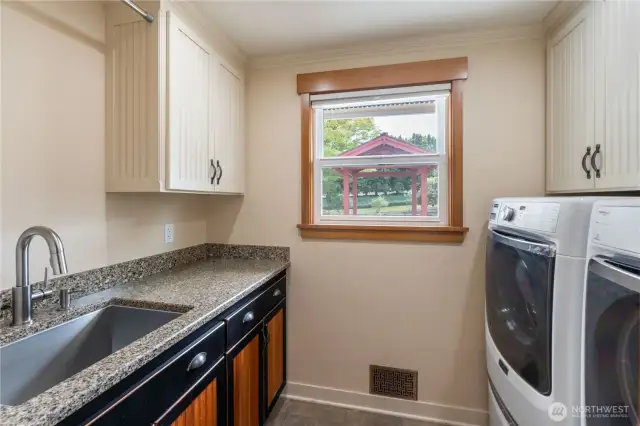 Utility room on main floor with wash basin on the left & elevated washer/dryer on the right