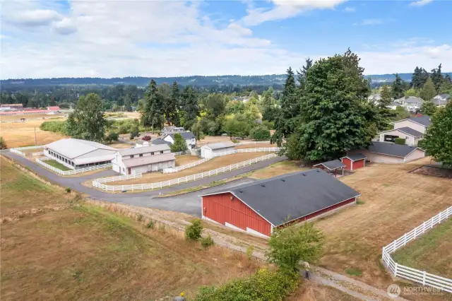 Picture from left side of property showing paved driveway leading past arena, barn & storage bldg, 10 car heated garage & up to 4 car/3 car garages and 2 car attached garage/home