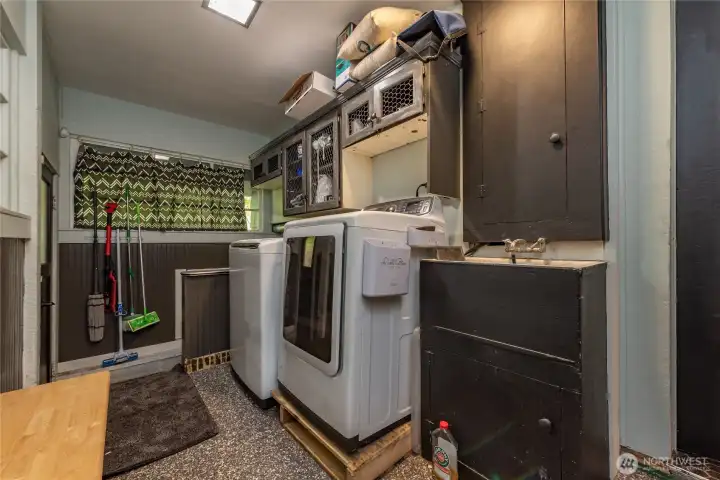 Spacious laundry room with sink. Door to the left gives you access to the outside, door to the right is from the kitchen.