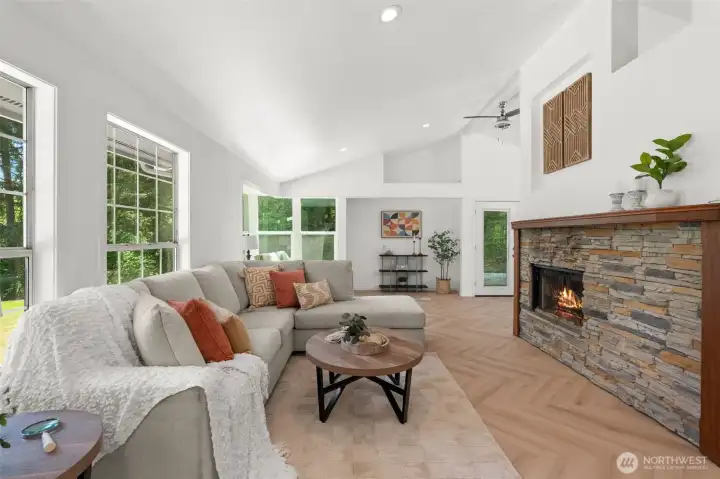 The living room has vaulted ceilings and a wood-burning fireplace. It opens to a reading nook and wraps around to the dining and kitchen The living room has vaulted ceilings and a wood-burning fireplace. It opens to a reading nook and wraps around to the dining and kitchen