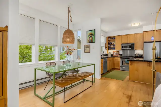 View to the dining nook and kitchen. The room has a western exposure and is bathed in natural light.