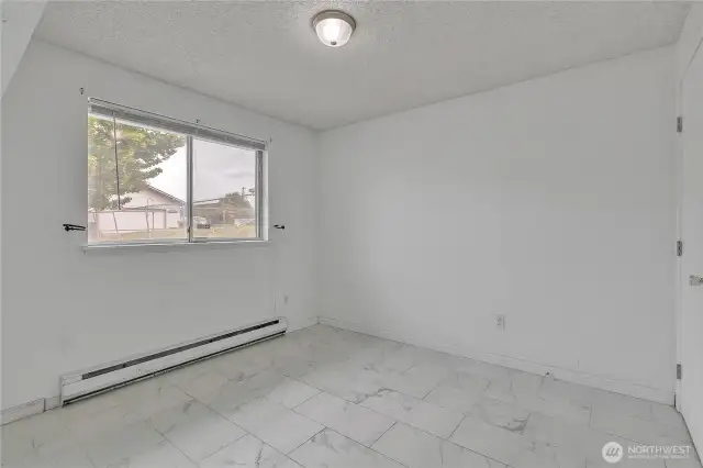 Primary Bedroom with tiled flooring and backyard view.