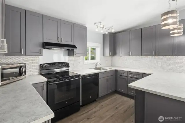 Kitchen features newer appliances, abundant cabinets and vinyl plank flooring.