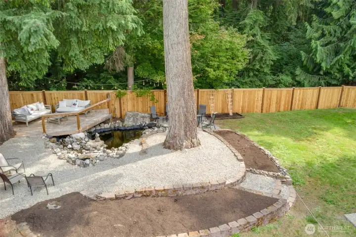 Drone view of the Deck and waterfall feature. Plenty of seating for entertaining, along with an area to plant flowers, shrubs, whatever you would like to personalize it!