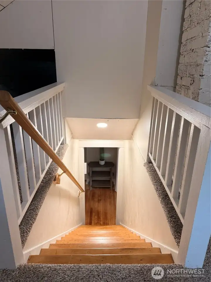 Freshly updated staircase leading to the upper-level bonus spaces, featuring brand-new plush carpeting, crisp white railings, warm wood handrails, and modern recessed lighting.