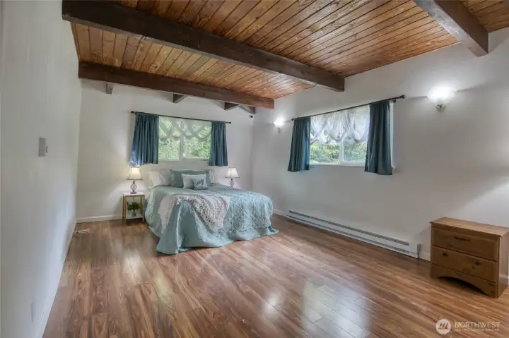 Primary bedroom with tongue in groove ceiling and laminate flooring Primary bedroom with tongue in groove ceiling and laminate flooring