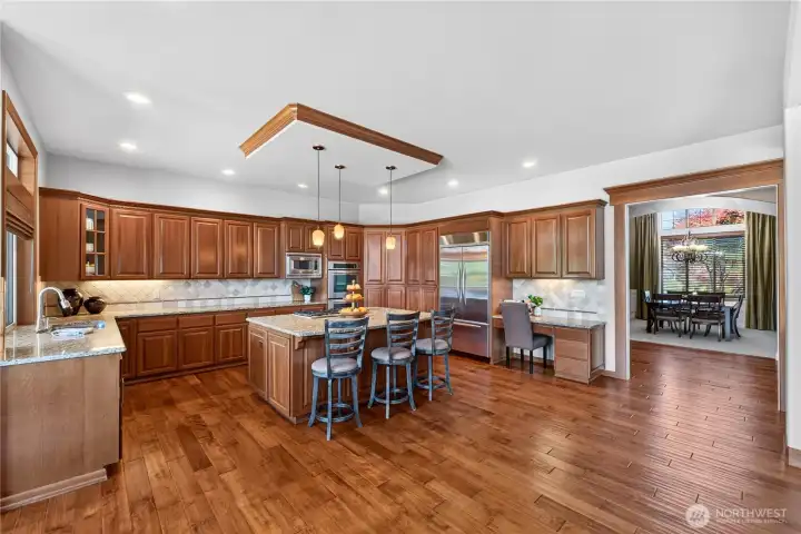 Gather in your Chef-inspired kitchen w/double ovens, SS appliances, Large island w/seating, tile back splash & desk space.