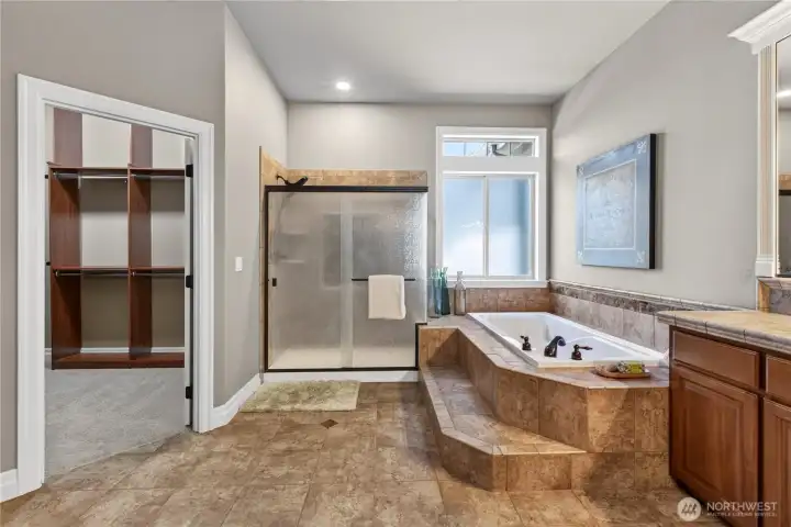 Primary bath w/soaking tub, tiled shower & walk-in closet w/built-ins.