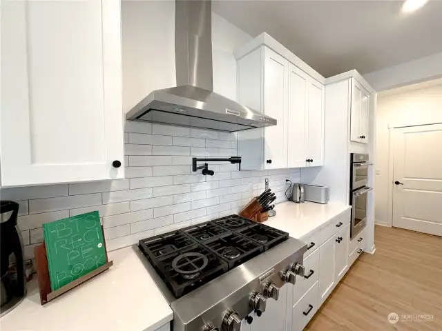 Builder upgraded kitchen to their top of the line model. Double ovens, 6 burner gas stove with tile backsplash, stainless hood and pot filler. Lots of storage, a walk-in pantry (out of frame on the right), a huge island and sliding door to the backyard covered patio.