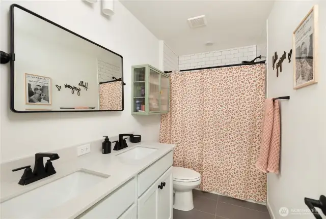 The upper-level full bathroom has double sinks and ceramic tile.