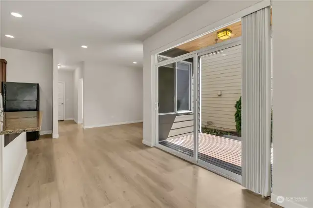 Back Deck and Private Side Yard. Dining Room area ahead and to the right. Hallway leads to Office, Garage, Storage Closet, and stairs to 2nd floor.