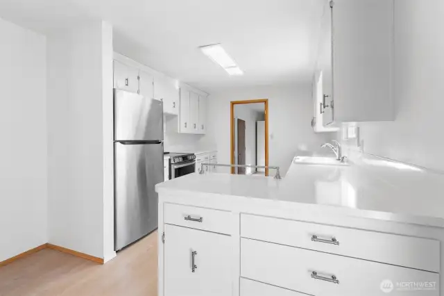 Crisp white Kitchen with solid counter and matching back splash.